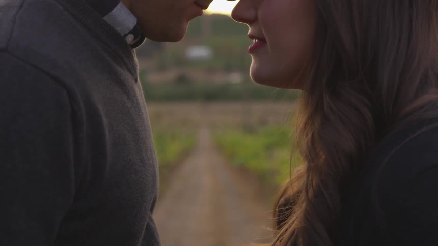 Man and woman stand close to each other in a grassy field
