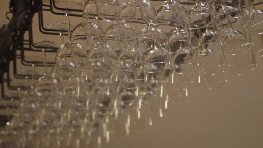 Wine glasses are hanging from a rack inside in daylight