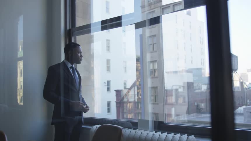 A man looks out the window on a cloudy day