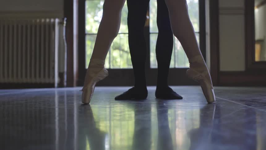 Man and woman practice ballet dancing in an empty room