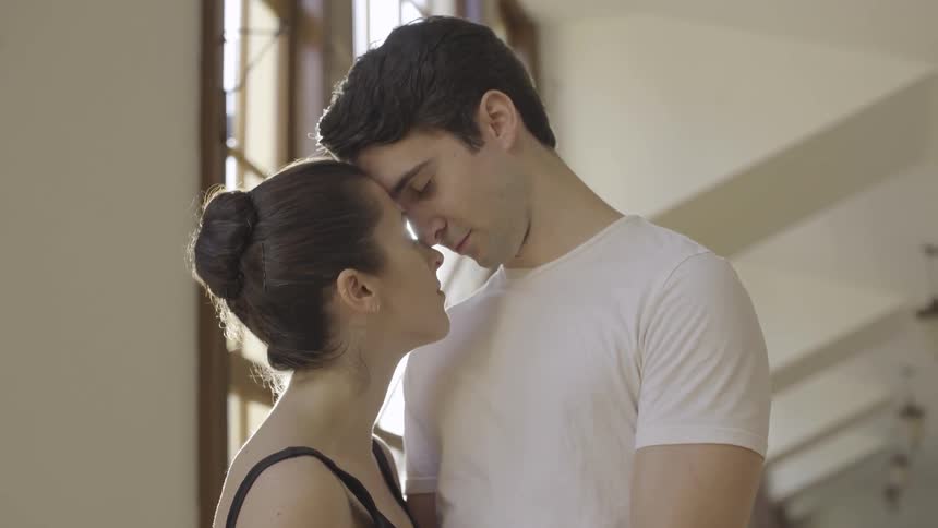 A man and woman lean together in the hall