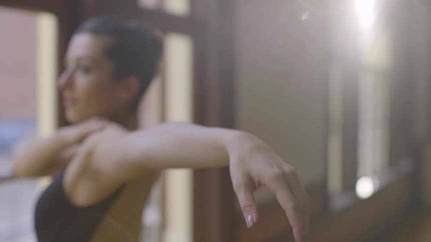 A ballerina stretches in a dance studio