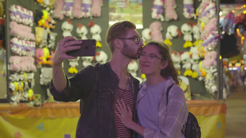 Man takes a pictures of himself and a woman at a carnival