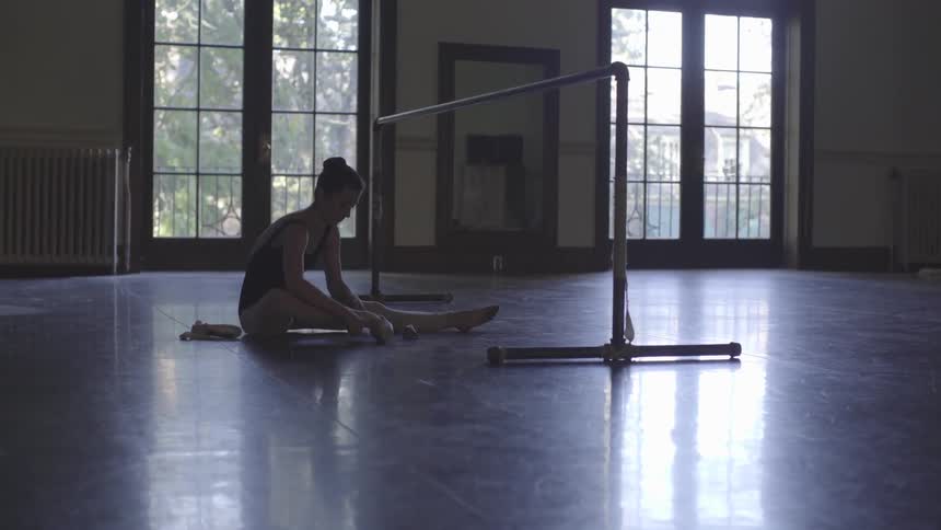 A ballerina is sitting on the floor