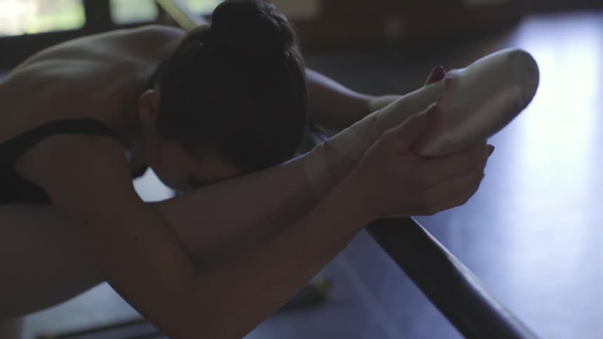 A ballerina stretches in a dance studio