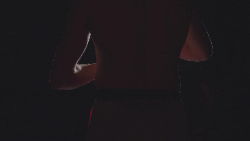 A person lifts red tape in a dark room