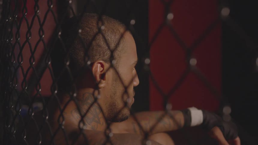 A man leans against the fence in the ring