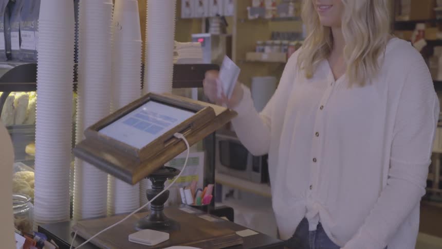 A customer is paying for their purchase at a coffee shop in daylight