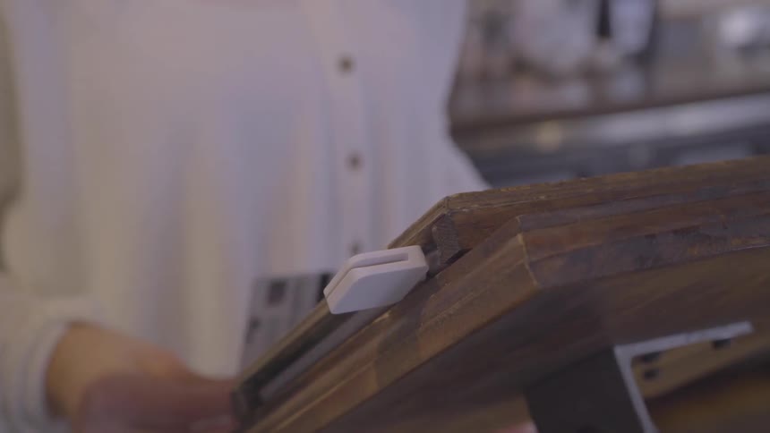 A clerk is scanning a credit card and handing it to the customer inside in daylight