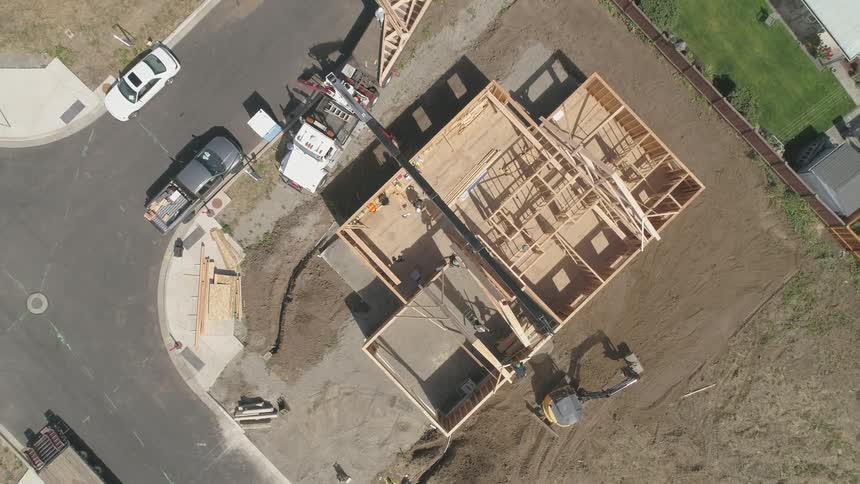 Crane on truck is carrying wood to place on house being built