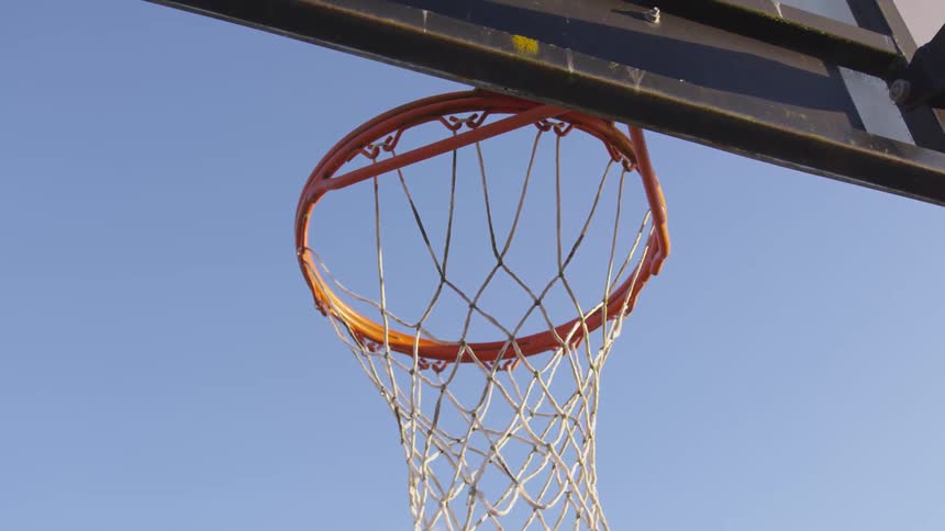 A basketball flies through an outdoor basketball hoop