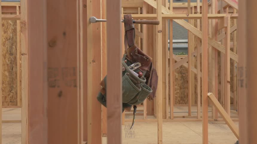 A construction worker's tool belt hangs from a hammer handle