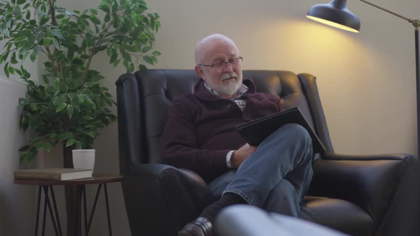 A man sits in the chair with a notepad