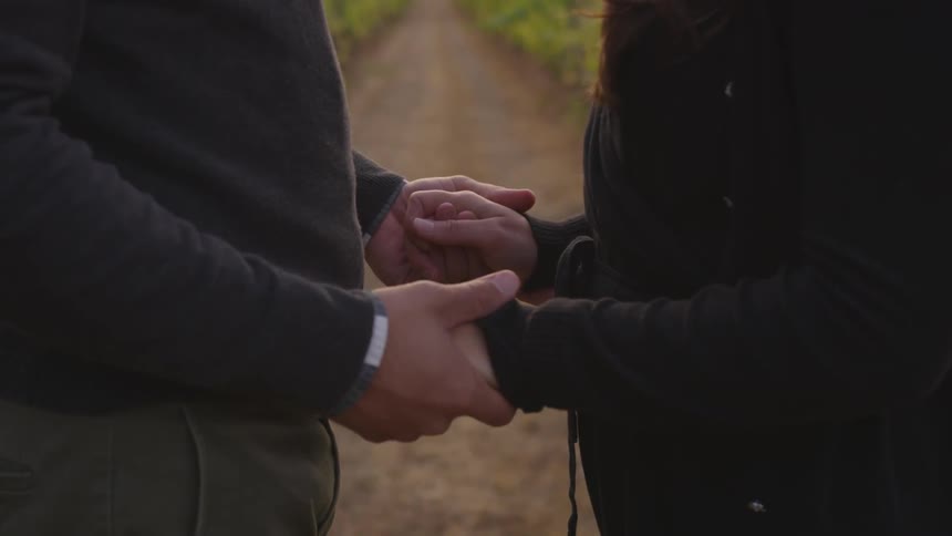 Man and woman hold hands outside in a field