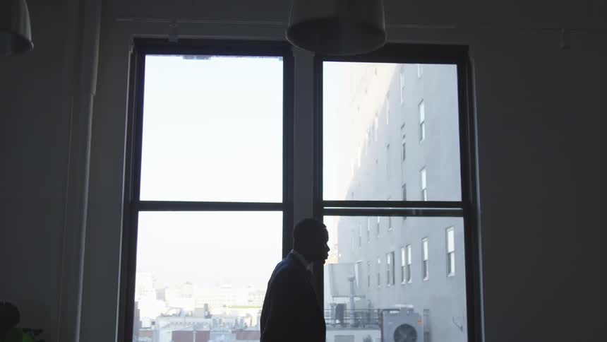 A businessman stands in front of a window