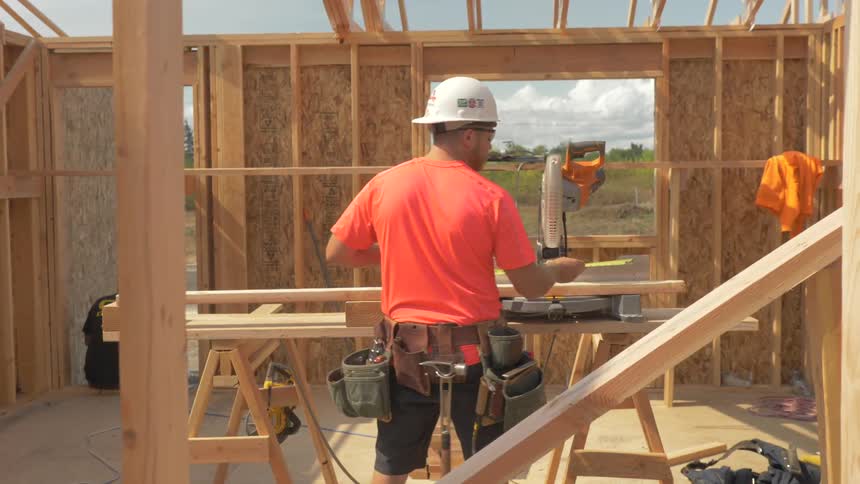 A builder measures a piece of lumber on a saw table