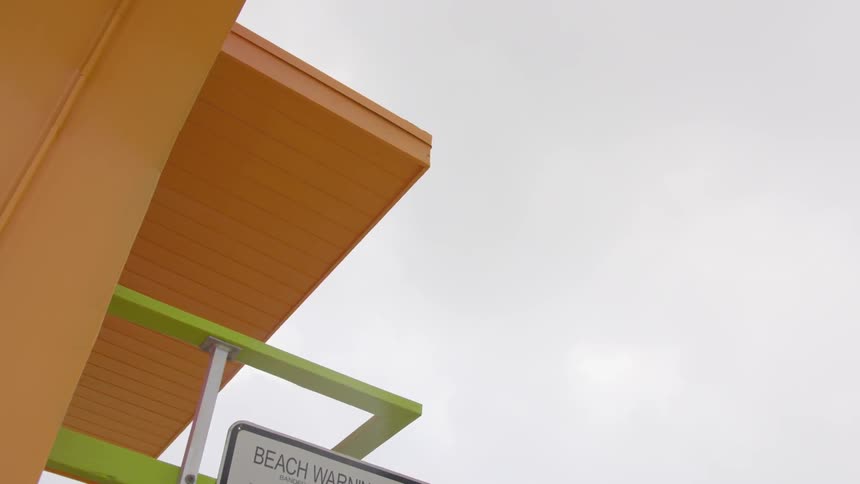 The lifeguard stand is orange with a sign on the side