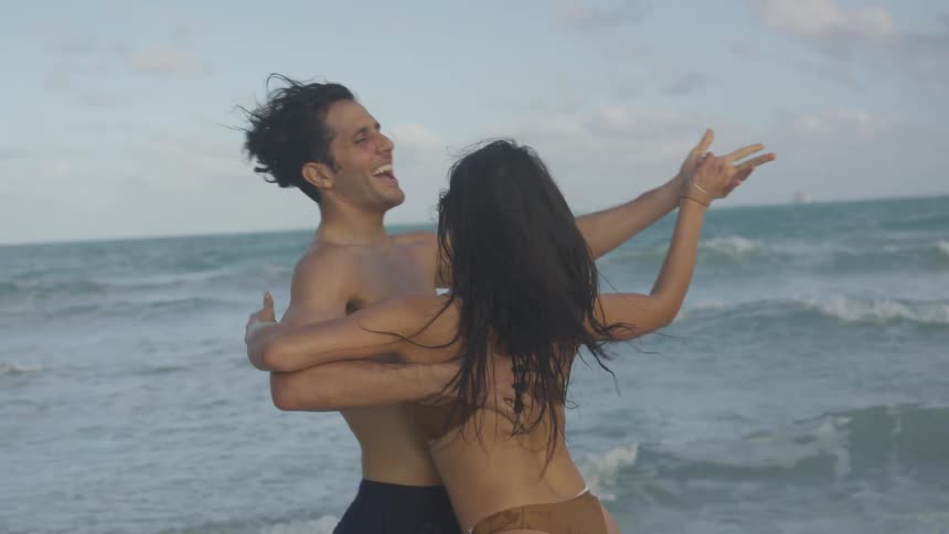 The woman and man dance on the beach