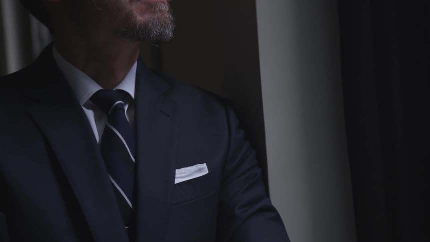 Man wearing a suit stands in a dim room