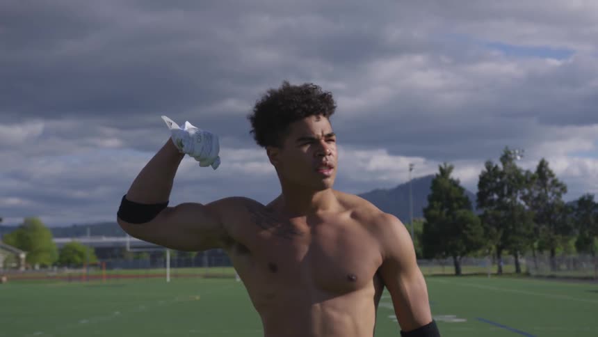 A football player flexes on an outdoor athletic field