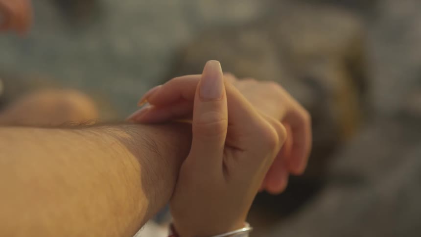 A woman is resting her hand on a man's arm outside in daylight