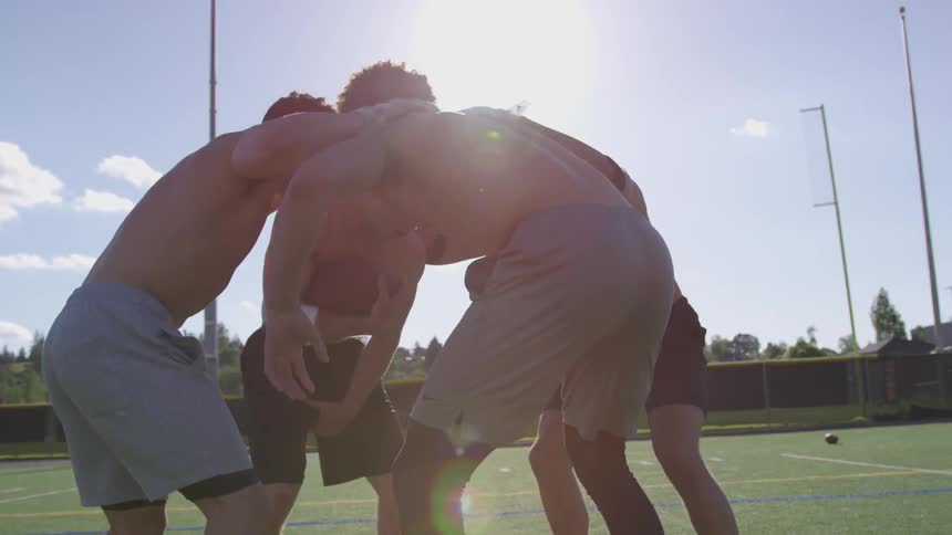 Football players huddle on an outdoor athletic field