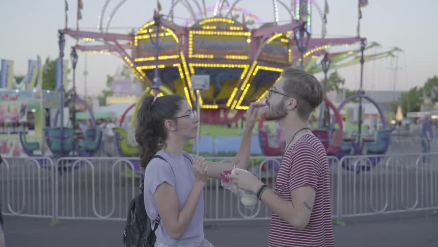 A couple shares cotton candy at the carnival