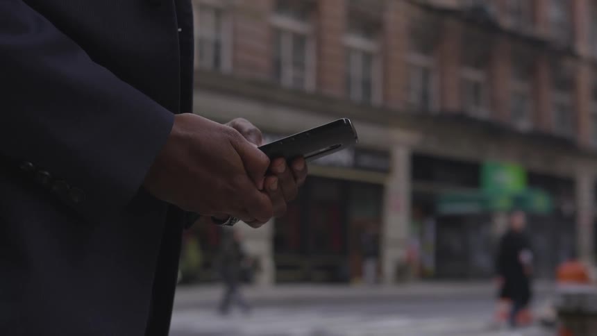 A businessman uses a phone on a city sidewalk