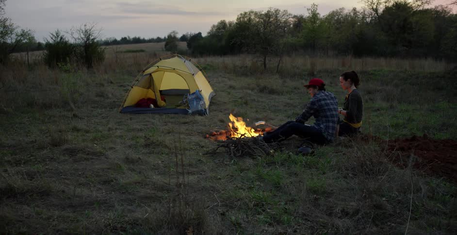 Man and a woman toasting marshmallows at their campsite
