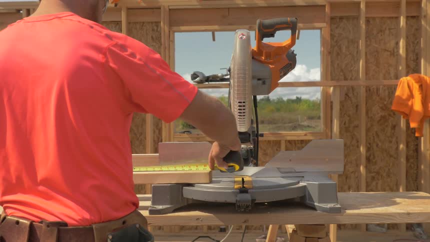 Man measures a piece of wood for it to be sawed