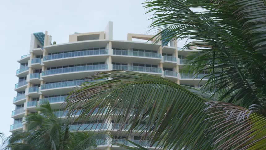 A large hotel building with trees in front of it on a sunny day
