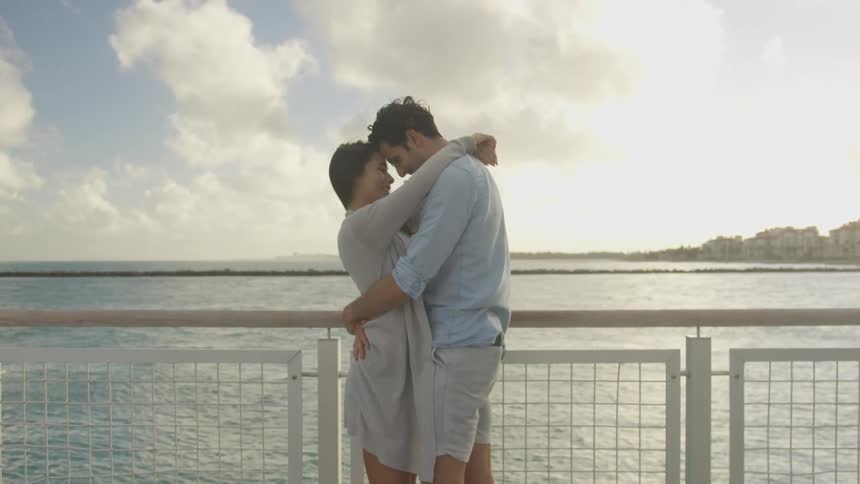 Man and woman hug next to a lake on a sunny day