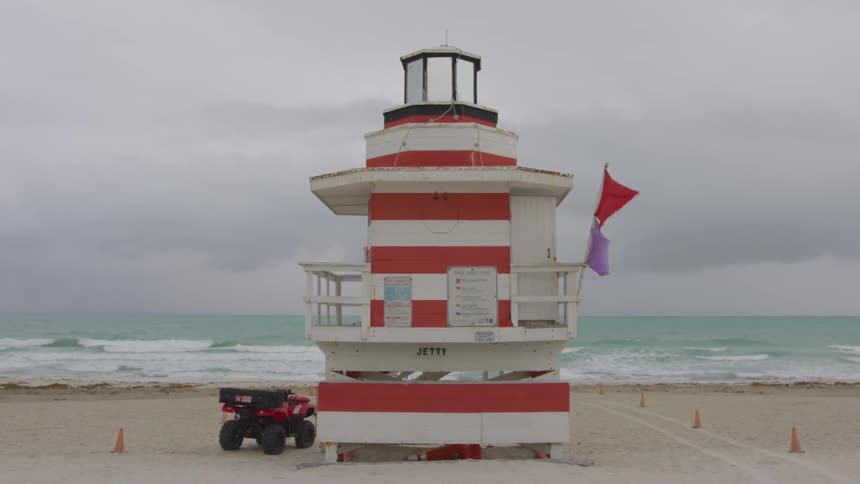 Flags on a red and white lifeguard shack blow in the wind