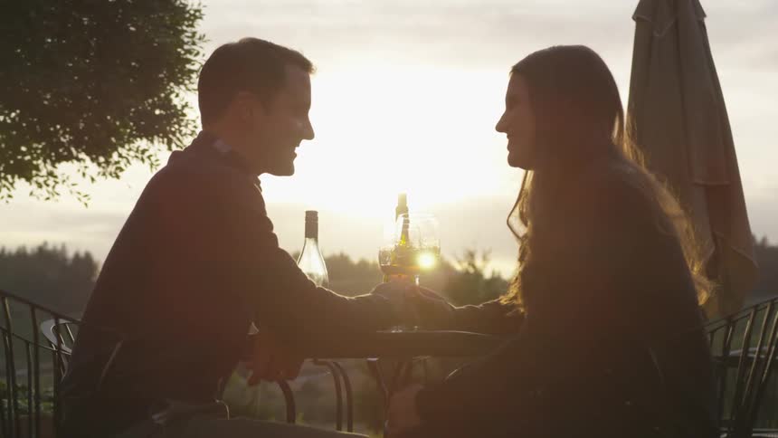 Man and woman sit at a cafe table as they smile at each other