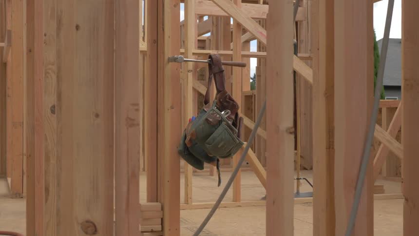 A tool belt hangs off a hammer handle at a construction site