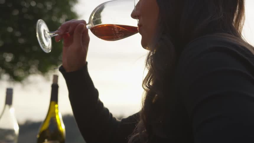 A woman takes a drink from her glass on a cloudy day