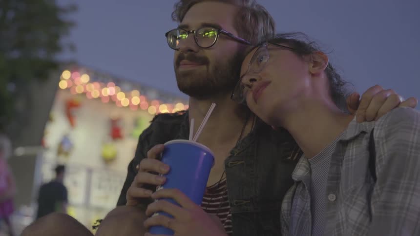 A woman leans her head on a man's shoulder at the carnival