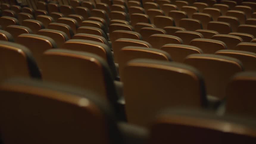 Rows of empty seats sit in an auditorium