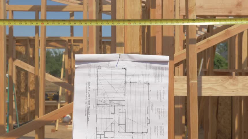 Blueprints are hanging from a frame at a construction project outside in daylight