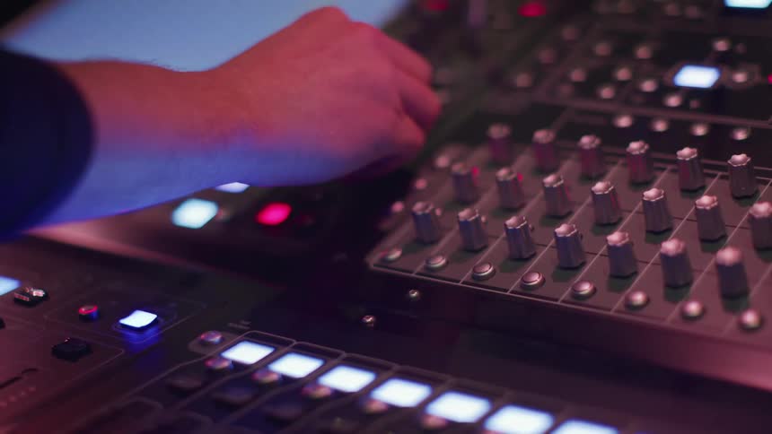 A man adjusts a knob on sound equipment