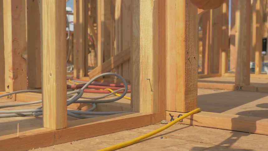 A construction worker is hammering a nail outside in daylight