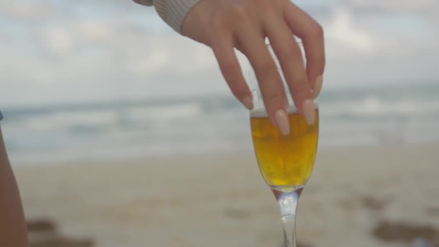 Woman holds a wine glass on the beach
