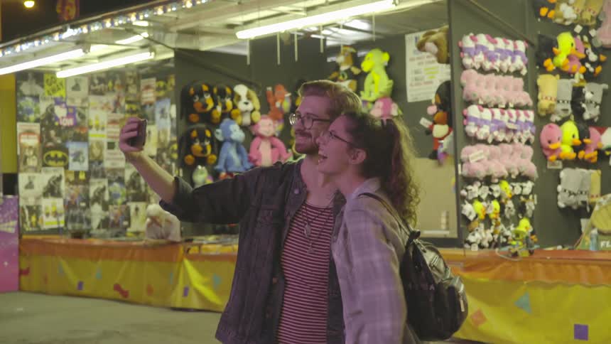 A couple take a photo at a carnival