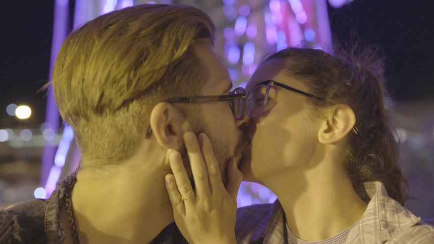 A couple kiss while riding on a ferris wheel at night