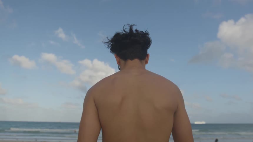 Shirtless man walks on the beach