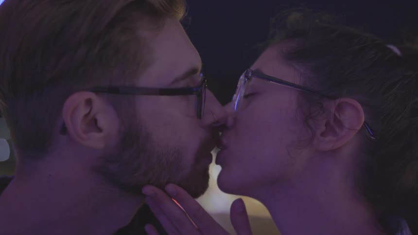 A man and woman kiss at night