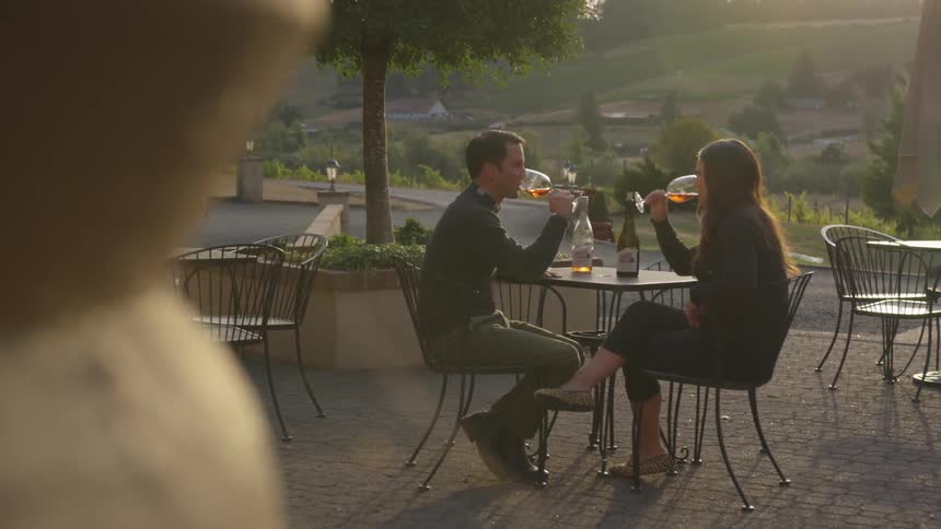 A couple sips wine at an outdoor table