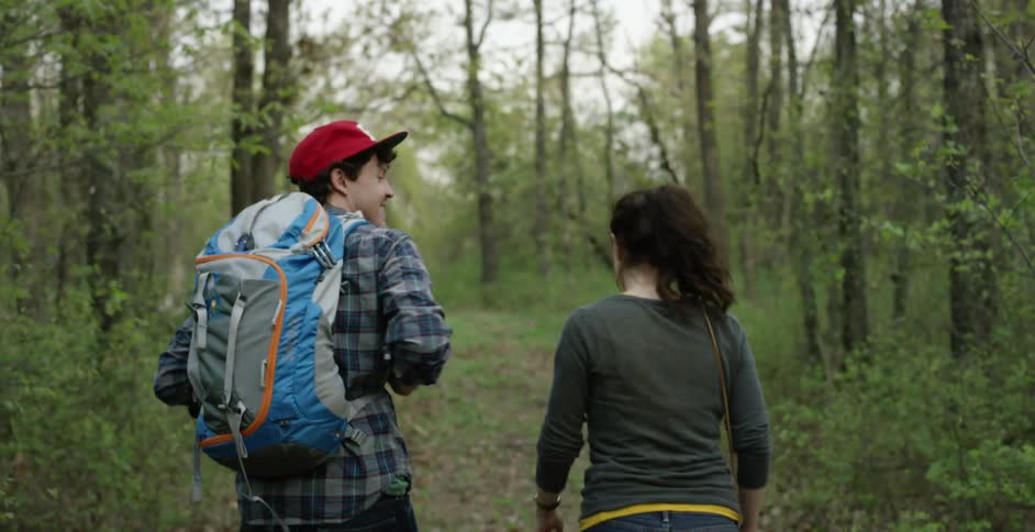 A man and woman talking while walking in the woods