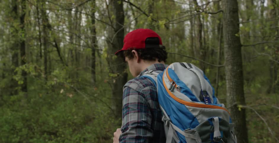 A man wearing a backpack hiking through some woods