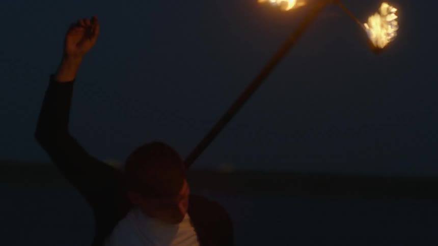 A man twirls a staff of fire